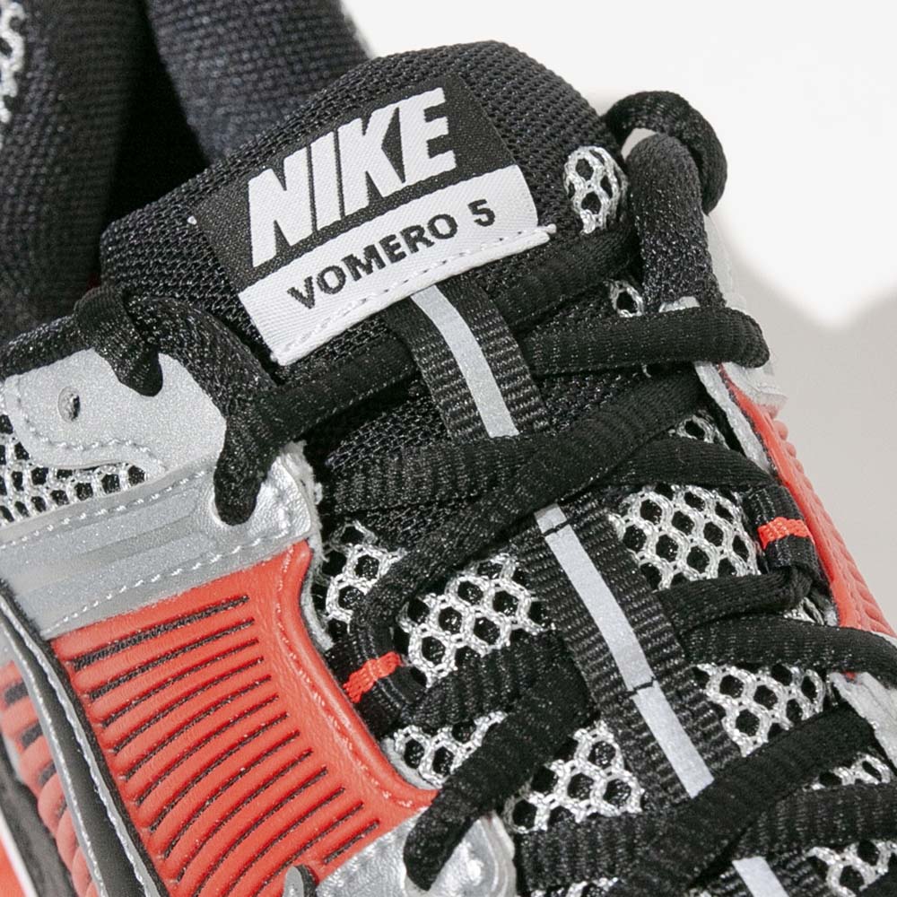 Close-up of Nike Zoom Vomero 5 tongue label showing Nike branding and ventilated upper materials.